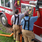 Firefighter Mike Chornack demonstrates pump operations to Firefighter Nolan Jackson