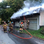 Burning embers shower down from a garage on fire during overhaul operations